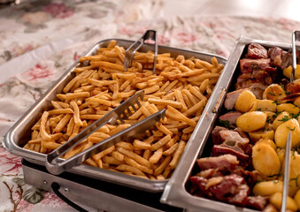 buffet table with meat and potatoes and french fries