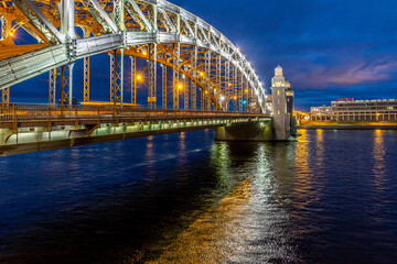 Naklejka premium Dusk perspective view of illuminated Bolsheokhtinsky Bridge with lights reflection in rippling Neva River water. Saint Petersburg, Russia.