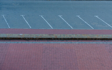 Empty parking lot with marked spaces and brick pavement