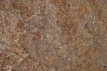 High-resolution close-up of natural granite rock surface with rough, weathered texture and earthy brown tones