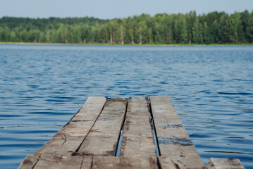 Fototapeta premium tranquil landscape, relaxing scene, wooden pier and country lake, blue water and green forest in smooth horizone line