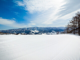 A freshly groomed ski slope with corduroy patterns and a view of the mountains in the background...