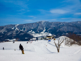 People enjoying skiing and snowboarding at the top of a ski resort with a distant valley view...