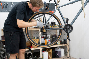 A mechanic is focused on cleaning the gears and chain of a bicycle using a specialized brush. This...