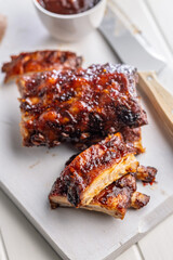 Pork BBQ glazed ribs on white cutting board.