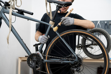 A mechanic is focused on cleaning the gears and chain of a bicycle using a specialized brush. This task is essential for maintaining the bike's efficiency and prolonging its lifespan.