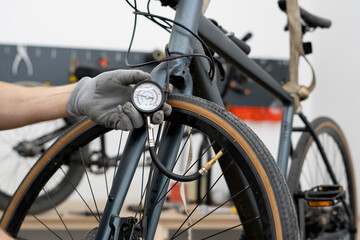 A person is adjusting the tire pressure of a bicycle using a hand-held gauge. The setting is a...