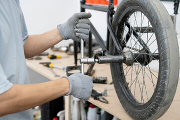 A worker removes BMX pegs from a bicycle in a busy bike shop with creating a lively atmosphere for...