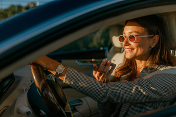 A fashionable woman enjoys driving her stylish car and sipping a beverage, showcasing luxury and...