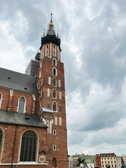 Historic Gothic church facade with tourists in a European city square in Krakow, Poland.