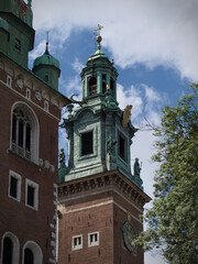 Historic church tower with a green copper roof and a sundial, set against a cloudy blue sky.