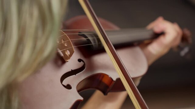 Violinist performing intricate melody with precise bow movements, creating expressive musical interpretation through intimate close-up of professional string instrument performance