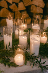 Decorative candles surrounded by greenery create a serene ambiance in a cozy indoor setting during winter