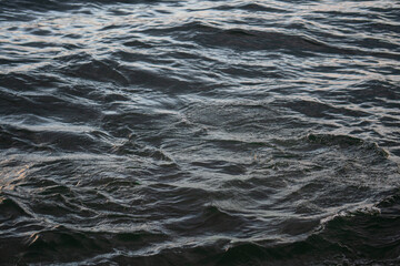 Tranquil scene of calm ocean or bay water with soft reflections under a clear sky.