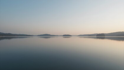 Fototapeta premium Calm lake reflecting the sky and distant land at early morning
