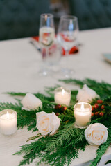 Elegant table setting with white roses, candles, and greenery for a special occasion celebration