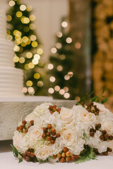 Elegant wedding floral arrangements featuring white roses and greenery set against a festive backdrop