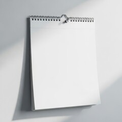 Blank spiral bound calendar page hanging on a wall with soft shadows isolated on white background