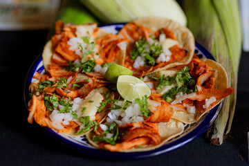 Mexican dish featuring tacos al pastor with pineapple, onion, cilantro, and lime slices served on corn tortillas, vibrant and flavorful.
