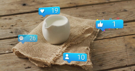 Showing white ceramic pitcher holding milk on burlap cloth on tabletop, with social media icons