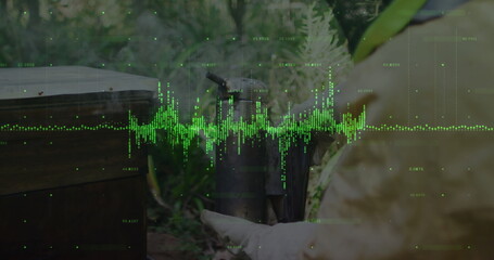 Beekeeper in yellow protective suit and gloves tending hive box using smoker at apiary, copy space