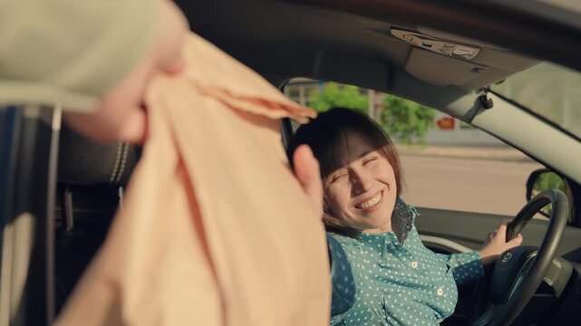 Food for driver, passenger to eat on road. Buying food in car. Woman passenger, food delivery to car in package. Fast food concept, delivery through auto window. Delicious meal, for travelers by auto.