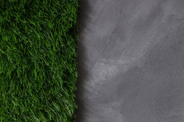 Green artificial grass and gray concrete wall background