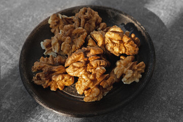 Walnuts, shelled. Close-up image of pile of shelled, halved walnuts in brown bowl, healthy food snack, wood grain background, elevated view.