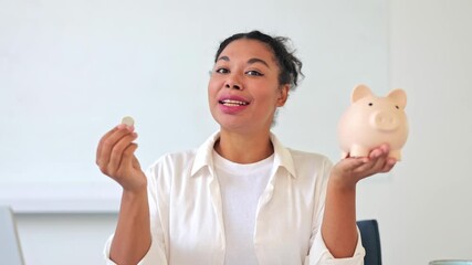 Confident businesswoman in a bright office setting, dressed in a white shirt, happily depositing a coin into a piggy bank. She symbolizes financial planning and smart saving for a secure future. - Powered by Adobe