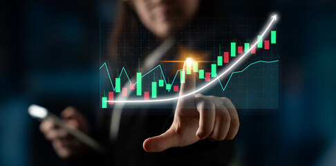 Business professional interacts with digital screen showing stock market trends, illustrating growth and analytics in a modern workspace environment. Impute