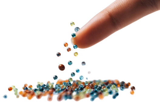 A finger dispenses colorful small beads onto a bed of similar beads