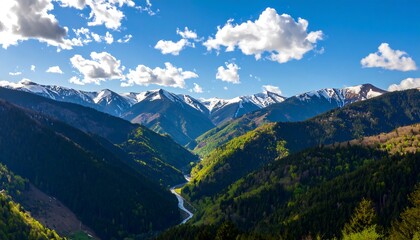 Obraz premium A breathtaking vista of snow-capped mountains and lush green valleys, showcasing a winding river carving its way through the landscape.