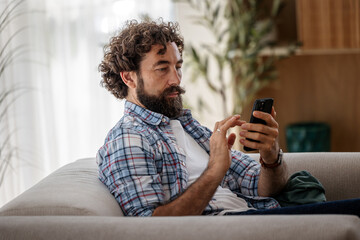 Married guy using his phone while sitting on a couch