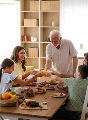 Happy family clinking glasses in toast at breakfast