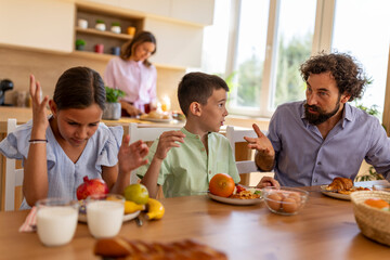 Kids arguing with their dad at breakfast table over food