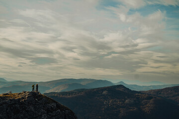 Hikers contemplating majestic mountain view under cloudy sky