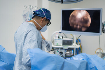 Urologist performing endoscopic surgery with monitor screen in operating room