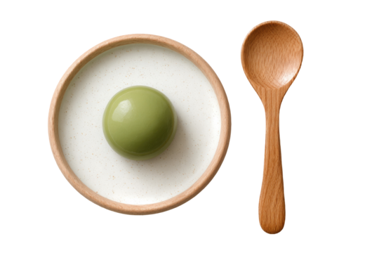 Light green sphere in a shallow bowl of white liquid, wooden spoon