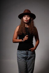 Young woman in hat, black shirt and jeans in the shadows