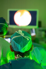 Surgeon observing endoscopic monitor during laser surgery in operating room
