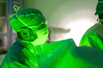 Surgeon wearing protective equipment during laser surgery with green light in operating room