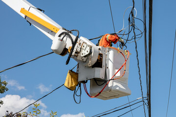 Electrical utility worker in bucket lift working on power lines maintenance