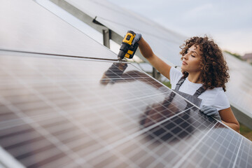 Female Technician Installing Solar Panel Using Cordless Drill