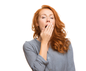 Tired red-haired woman yawning with her hand over her mouth, isolated.