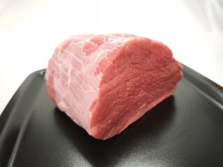 A piece of beef meat on a black plate in close-up. Raw meat