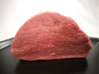 A piece of beef meat on a black plate in close-up. Raw meat