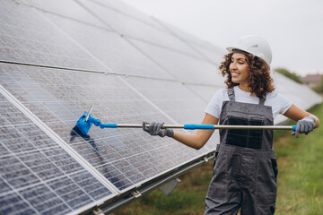 Female technician cleaning solar panels for renewable energy production