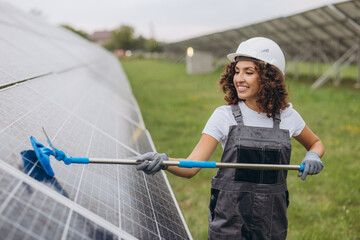 Female engineer cleaning solar panels in a large photovoltaic plant