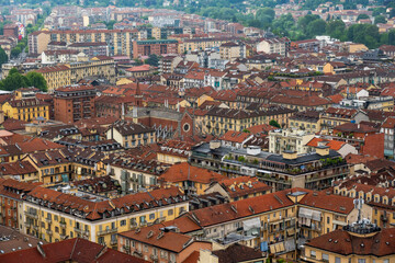 Fototapeta premium Aerial scene of Torino showcasing red-tiled rooftops of historic buildings and a scenic neighborhood.