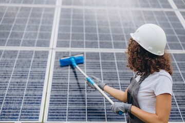 Female technician cleaning solar panels for renewable energy production